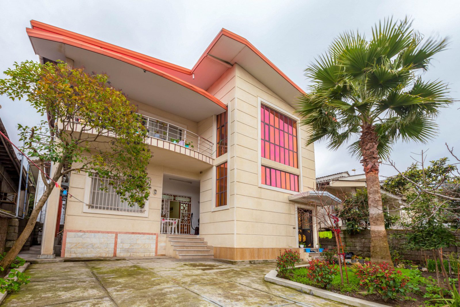 طراحی نمای مدرن ویلای دوبلکس با سنگ کرم و پنجره‌های رفلکس همراه با محوطه‌سازی حیاط و درخت نخل