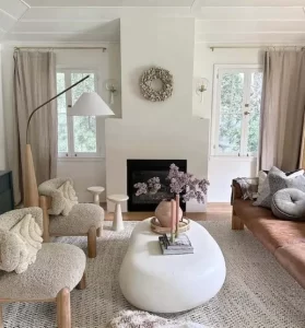 چراغ ایستاده خمیده کنار مبل در نشیمن مینیمال؛ شید سفید، نور محیطی یکنواخت و دکور خنثی