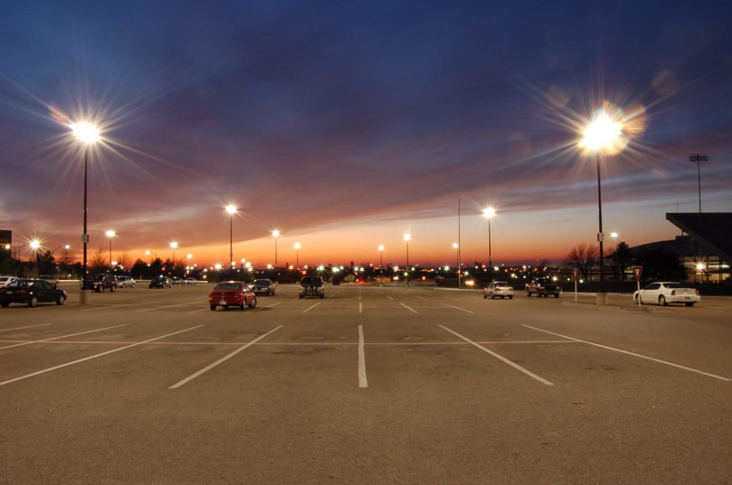 پارکینگ وسیع با نور غروب و چراغ‌های خیابانی