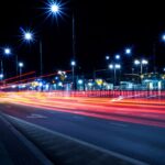 نمای شبانه یک خیابان شهری با روشنایی چراغ های خیابانی LED و رد نور خودروها؛ نور سفید یکنواخت برای افزایش دید و ایمنی معابر